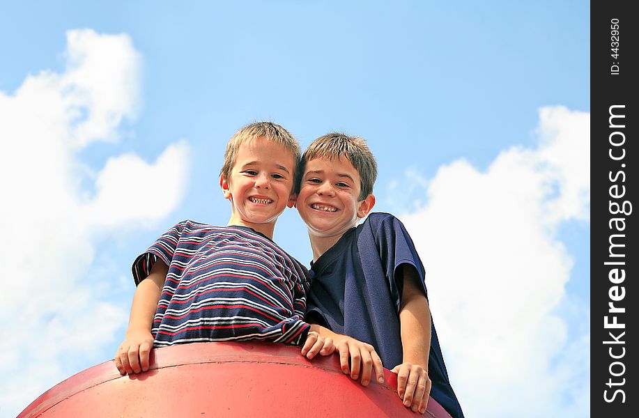 Brothers Playing on a Playground with the Blue Cloudy Sky in the Background