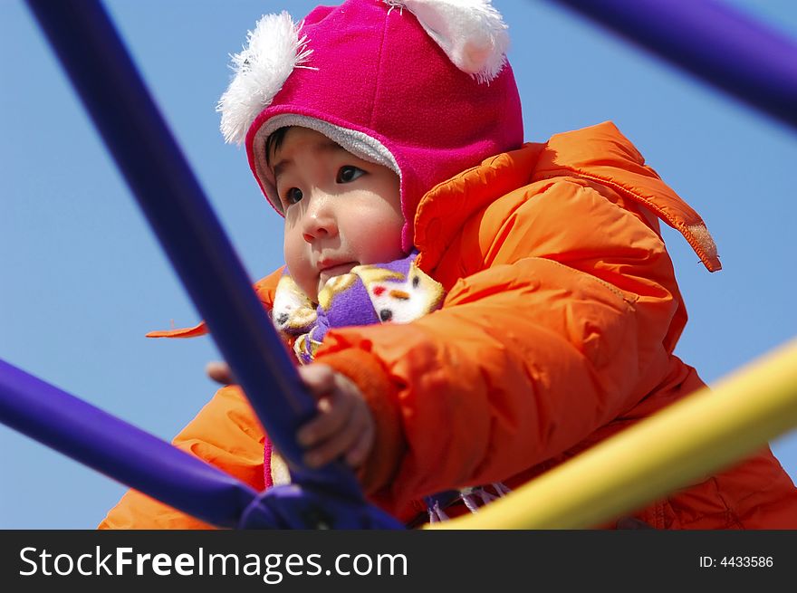 An Chinese little girl playing on climbing frame in winter