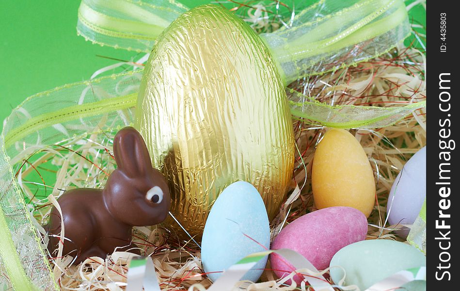 Assortment of chocolate Easter eggs wrapped in colorful paper and ribbon with edible chocolate bunny. Assortment of chocolate Easter eggs wrapped in colorful paper and ribbon with edible chocolate bunny