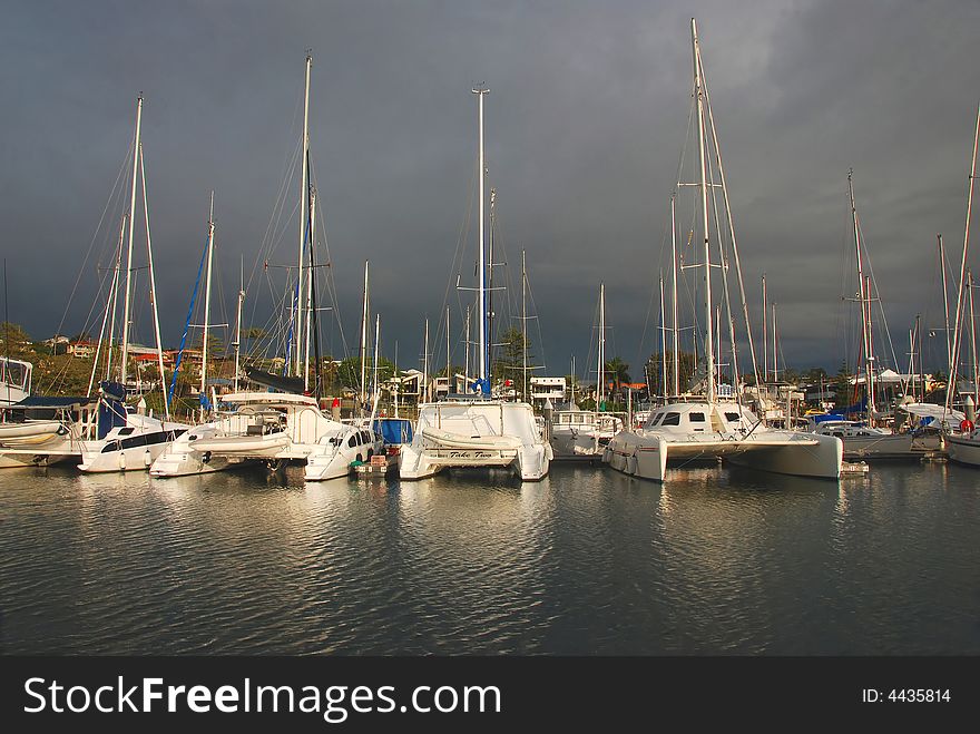 Catermarans tied up in a marina as storm clouds gather overhead. Catermarans tied up in a marina as storm clouds gather overhead