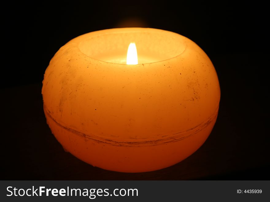 One yellow candle and black background. One yellow candle and black background