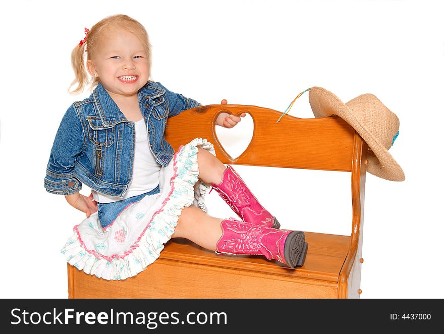 Young cowgirl on bench with hat and boots. Young cowgirl on bench with hat and boots