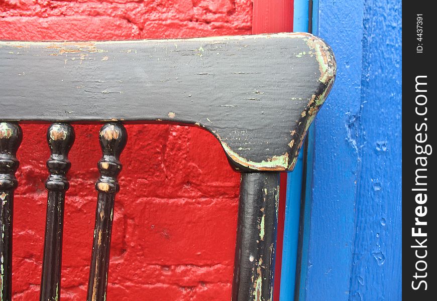 Old chair set against a brightly painted wall. Old chair set against a brightly painted wall