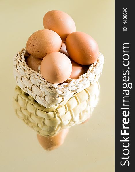 Still life of farm-fresh eggs in a basket on a reflective surface