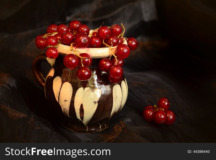 A clay cup with red currants full of fruits. A clay cup with red currants full of fruits