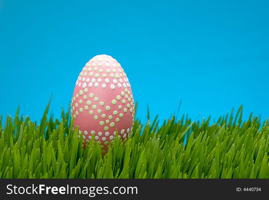 An image of a pastel easter egg in lush grass