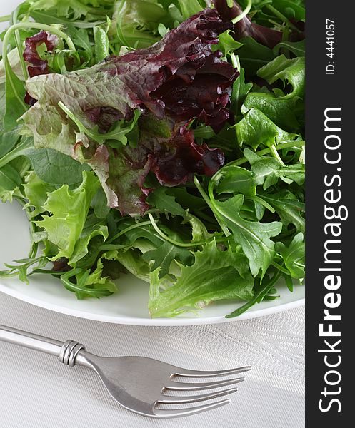 Fresh leaf salad with fork on gray  tea-cloth