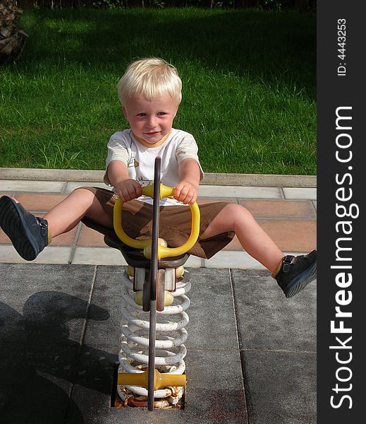Young Boy Swinging At Playground