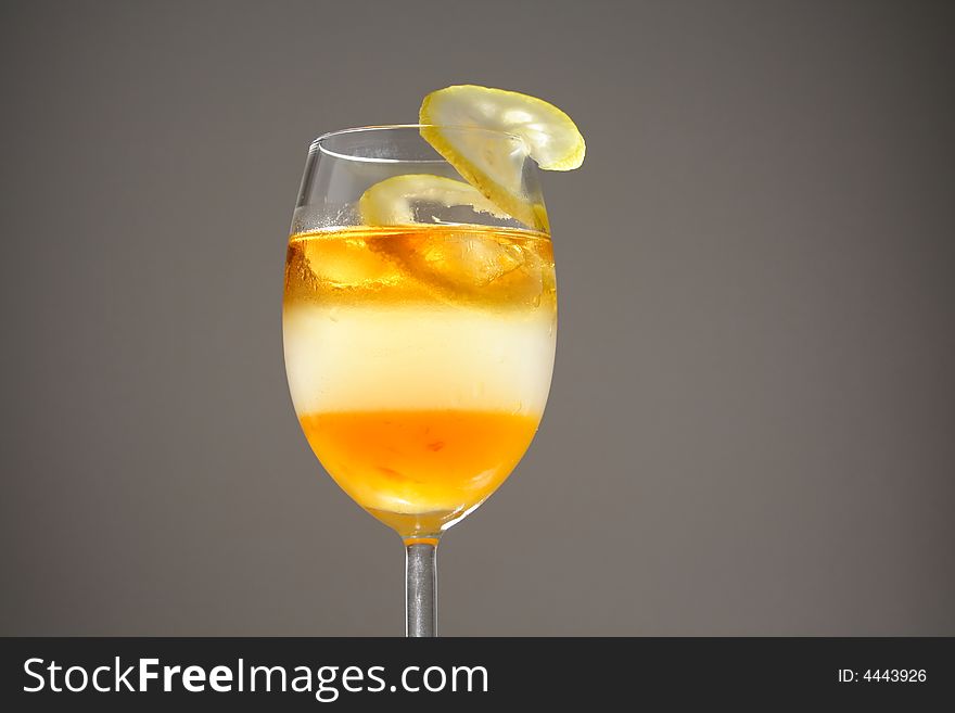 Triple layered drink with spiral lemon slice in studio light