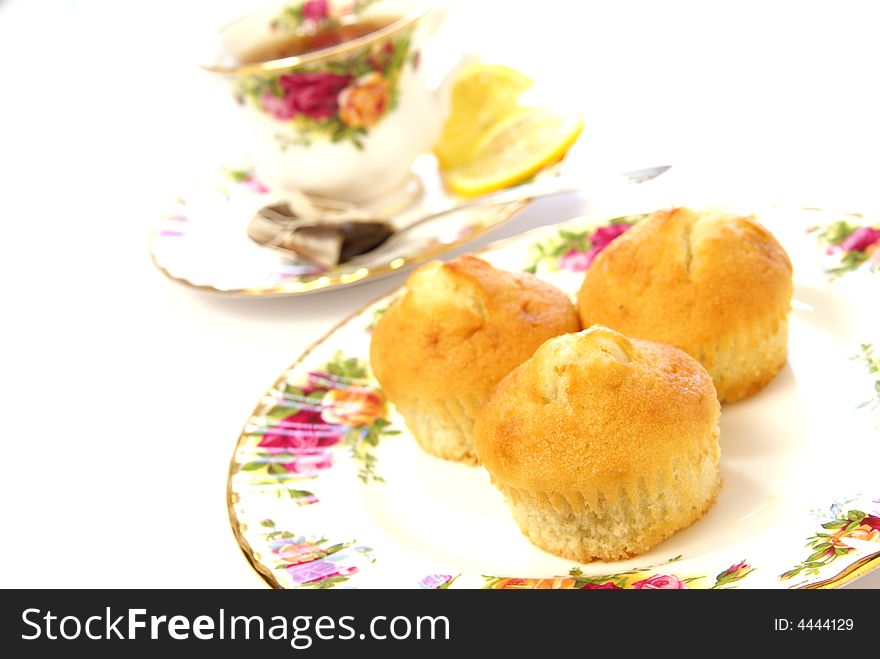 Three cake muffins on beautiful plate with cup of tea in the background. Three cake muffins on beautiful plate with cup of tea in the background