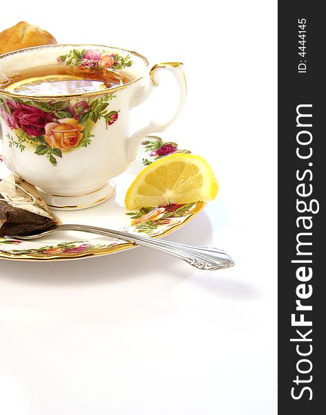 Beautiful cup of tea with lemon and spoon on a matching saucer. Beautiful cup of tea with lemon and spoon on a matching saucer