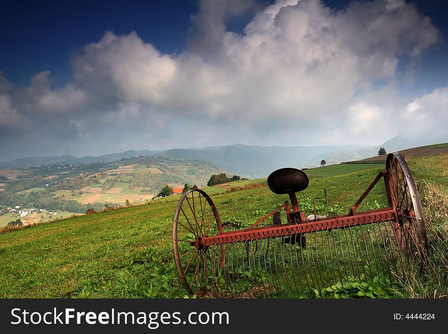 Raking machine on the meadow in summer day