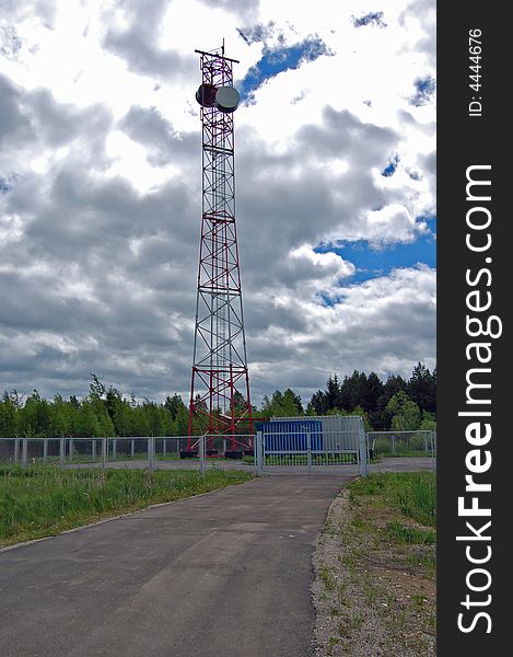 The fenced object of radiorelay communication. A tower with two aerials. Two technological containers. All object on a background of a wood and the deep cloudy sky. The fenced object of radiorelay communication. A tower with two aerials. Two technological containers. All object on a background of a wood and the deep cloudy sky.