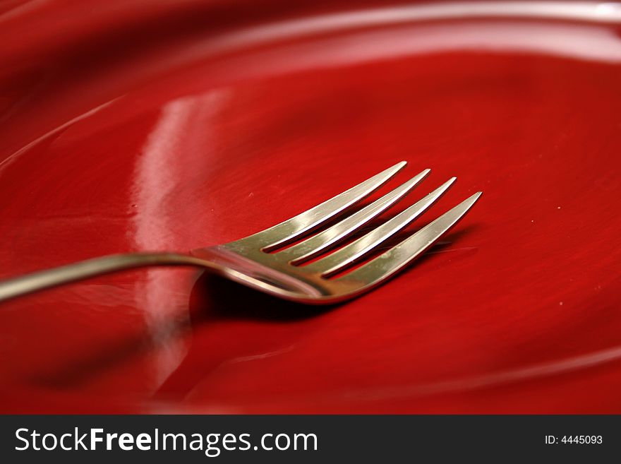 A fork on a red plate that was on my table during a recent dinner. A fork on a red plate that was on my table during a recent dinner