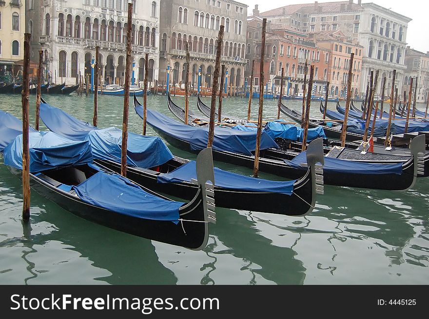 Gondolas parked in a row on canal, Venice, Veneto region, Italy. Gondolas parked in a row on canal, Venice, Veneto region, Italy.