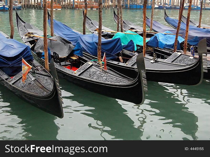 Gondolas parked in a row on canal, Venice, Veneto region, Italy. Gondolas parked in a row on canal, Venice, Veneto region, Italy.