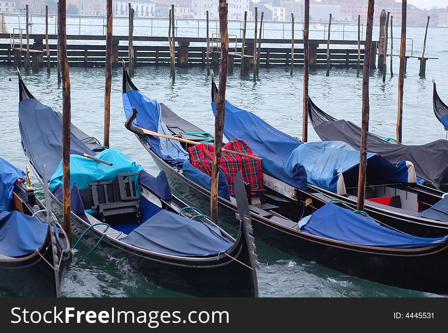 Gondolas parked in a row on canal, Venice, Veneto region, Italy. Gondolas parked in a row on canal, Venice, Veneto region, Italy.