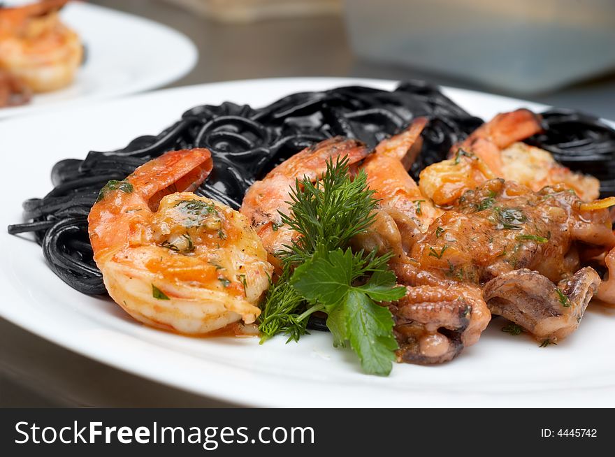 Fried shrimps with exotic black spaghetti tinted by cuttlefish ink. Fried shrimps with exotic black spaghetti tinted by cuttlefish ink
