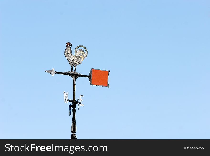 A silver rooster weather vane points west. A silver rooster weather vane points west