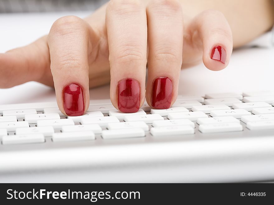 Fingers with red nail typing on keyboard