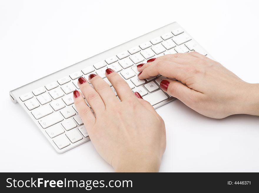 Fingers with red nail typing on keyboard