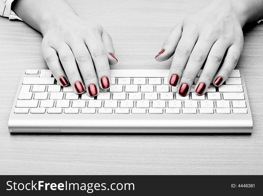 Fingers with red nail typing on keyboard