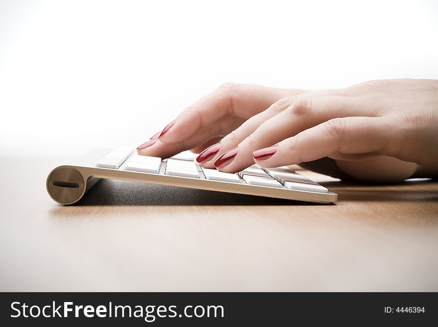 Fingers with red nail typing on keyboard