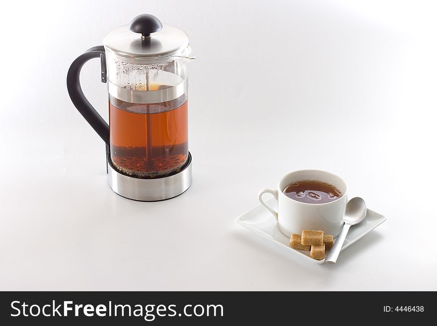 A cup of tea and a tea brewer isolated on white background. A cup of tea and a tea brewer isolated on white background.