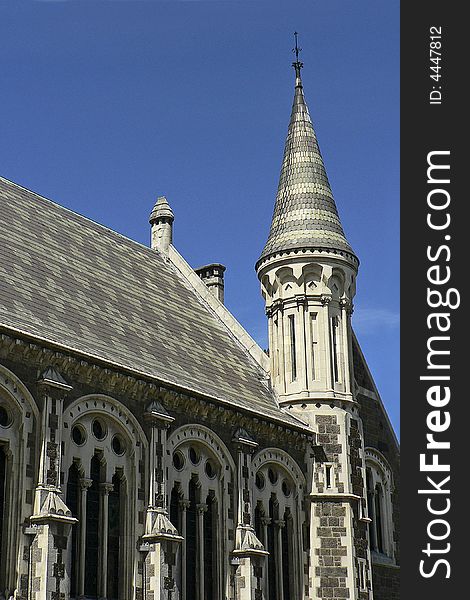 Section of the cathedral in Christchurch's Cathedral Square, showing decorative roof tiling window arches and an ornate bell tower