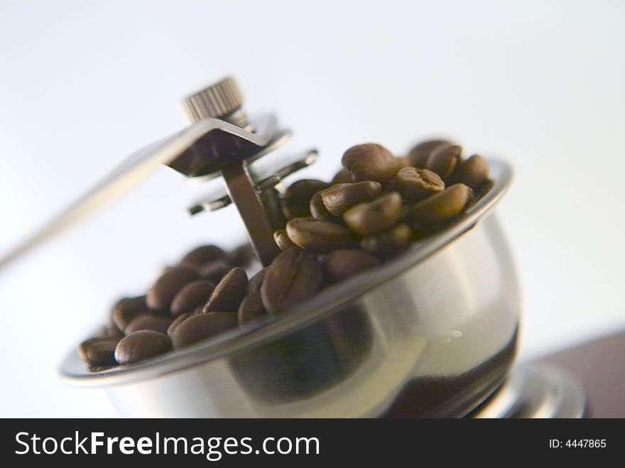 A nice small coffee grinder with coffee seeds. A nice small coffee grinder with coffee seeds