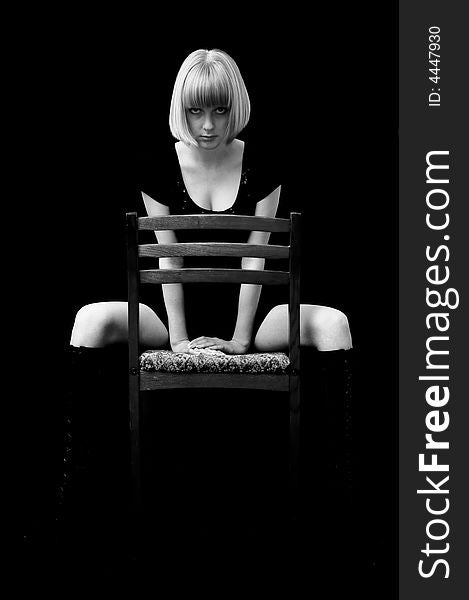 Blonde with a passionate sight sits on a chair. Monochrome