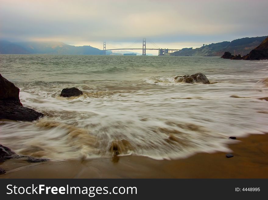 Golden Gate Bridge at sunset with waves in foreground, San Francisco. Golden Gate Bridge at sunset with waves in foreground, San Francisco