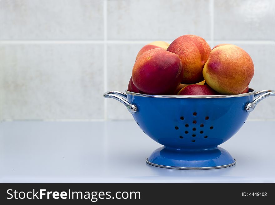 Blue bowl of nutritious nectarines on a kitchen counter. Blue bowl of nutritious nectarines on a kitchen counter