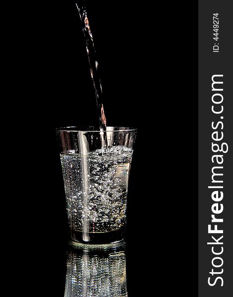 Jet of water fills in a glass. Isolated on black. Jet of water fills in a glass. Isolated on black.