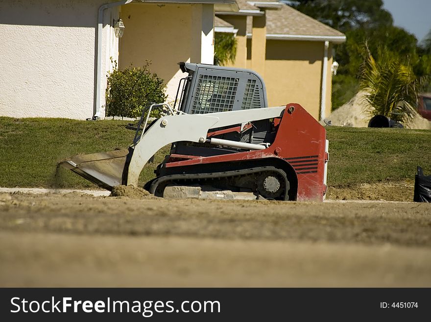 A midget bulldozer-like tractor cleaning up a job site