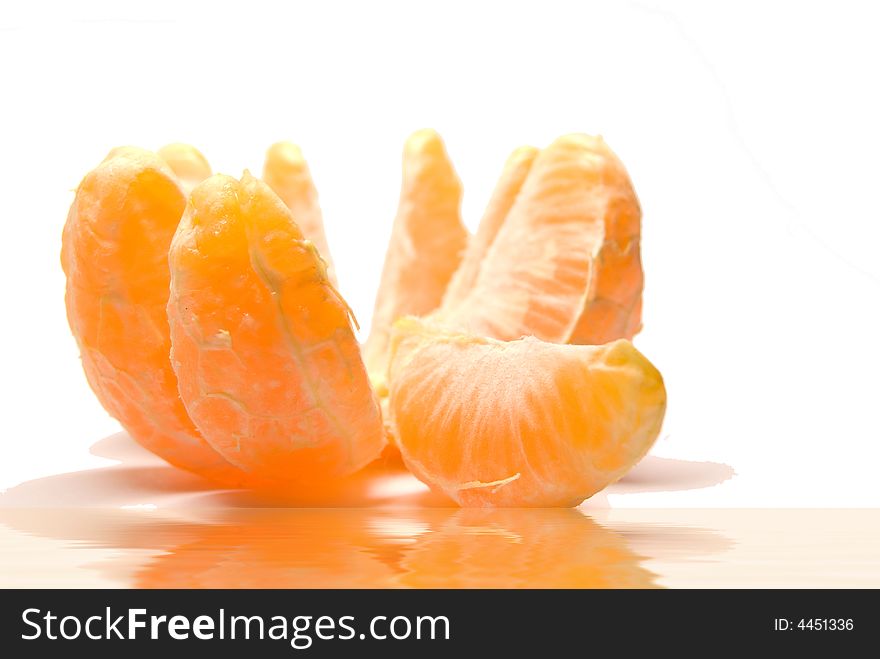 The beautiful orange ripe tangerine of a segment is reflected in water in a white background. The beautiful orange ripe tangerine of a segment is reflected in water in a white background