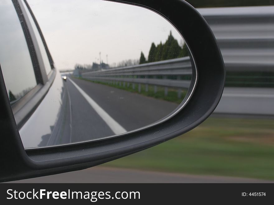 Car driving, side of the road reflecting in the mirror