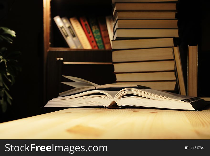 Various books on wooden table on background with evening home interior. Various books on wooden table on background with evening home interior