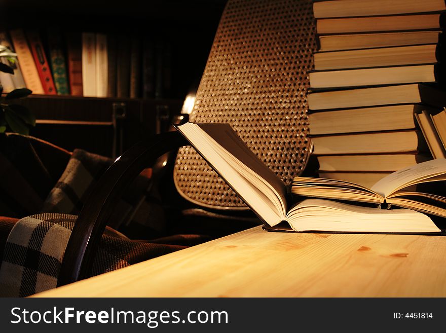 Various books on wooden table on background with evening home interior. Various books on wooden table on background with evening home interior
