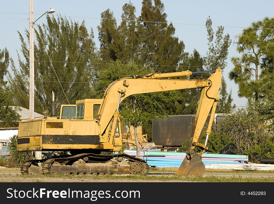 A backhoe at a job site while the operator is in a meeting