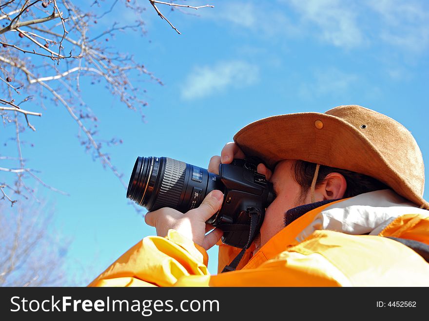 Young man taking picture outdoor, blue sky in background. Young man taking picture outdoor, blue sky in background.