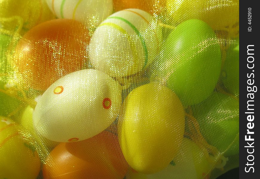 Colored little easter eggs under yellow veil