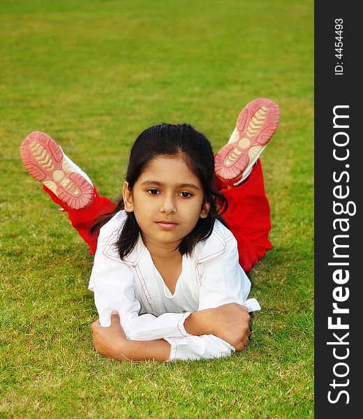 A cute Indian girl lying on a green grass lawn. A cute Indian girl lying on a green grass lawn.