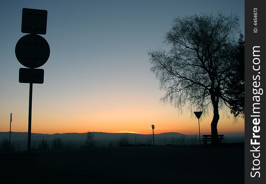 Sunset and the silhouette of the tree and the traffic sing. Sunset and the silhouette of the tree and the traffic sing
