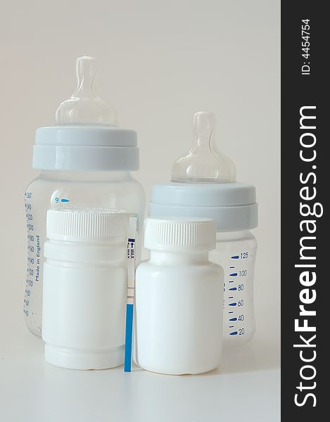 Confirmative pregnancy test, two drug's (vitamins) bottles and two small baby's bottles. Confirmative pregnancy test, two drug's (vitamins) bottles and two small baby's bottles.