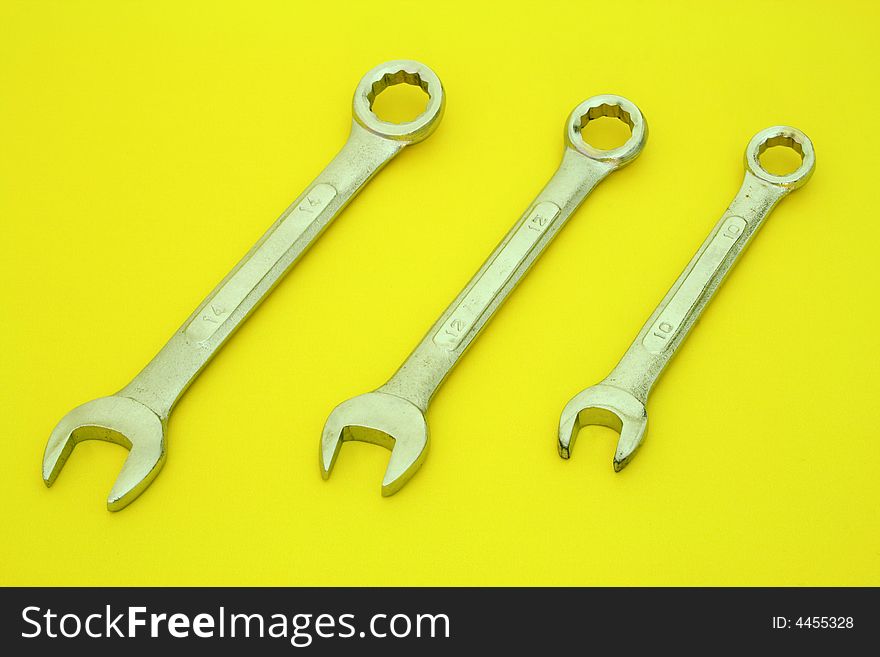 Three wrenches on a yellow surface