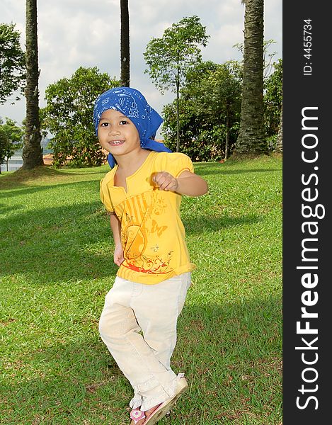 A little girl wearing bandana covering her head at the park. A little girl wearing bandana covering her head at the park.