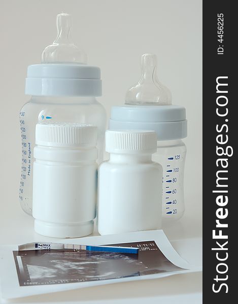 Confirmative pregnancy test, two drug's (vitamins) bottles, two small baby's bottles and ultrasound picture. Confirmative pregnancy test, two drug's (vitamins) bottles, two small baby's bottles and ultrasound picture.