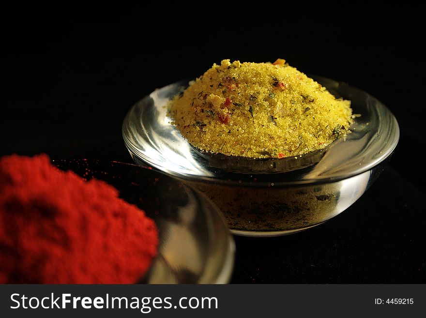 Mixed herb in a glass bowl with paprika on the foreground.