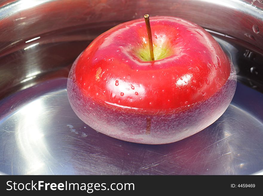 Red Apple floating around in a pot with water. Red Apple floating around in a pot with water.